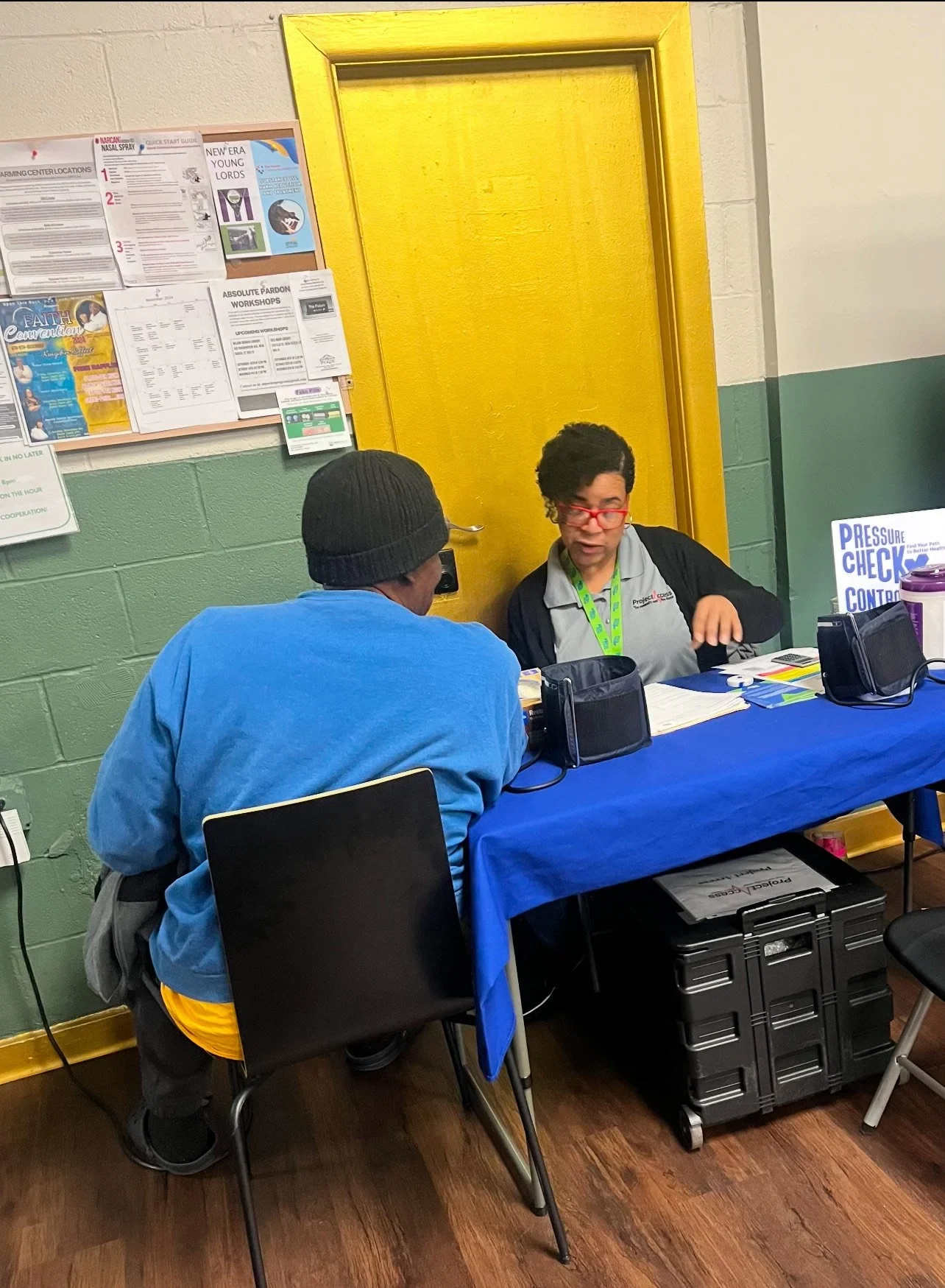 A guest receiving a health check-in from community partners at the Upon This Rock warming center